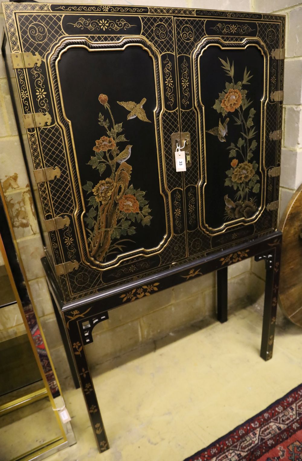 A Chinese black-lacquered and painted cabinet on stand, width 106cm, depth 46cm, height 173cm